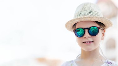 Hasır şapkalı, güneş gözlüklü, fotokopi alanı olan gülümseyen kız, açık havada şık bir yaz portresi, seyahat ve parlak arka planlı yaşam tarzı konsepti.