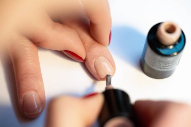 Profesyonel manikür, fırçayla çıplak jel cilası sürme, zarif doğal tırnakların yakın çekimi ve açık şişe, kuaförde ya da kaplıcada hassas güzellik tedavisi