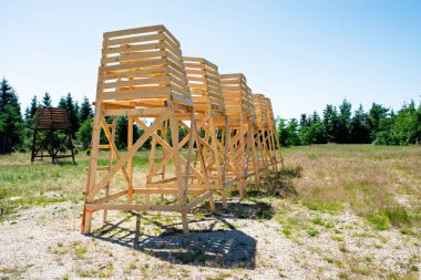 Açık alanda merdivenleri olan yüksek ahşap gözlem platformları, açık mavi gökyüzü, mühendislik ve marangozluk kavramına karşı yapım aşamasındaki modüler kereste iskelesi iskelesi