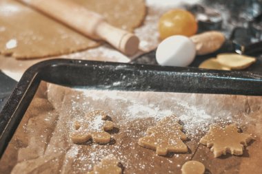 Karanlık bir arka planda Noel kurabiyesi pişirmek. Zencefilli ekmeği hamurdan kes. Manzara, tarçınlı çiğ hamur ve zencefilli ekmek..