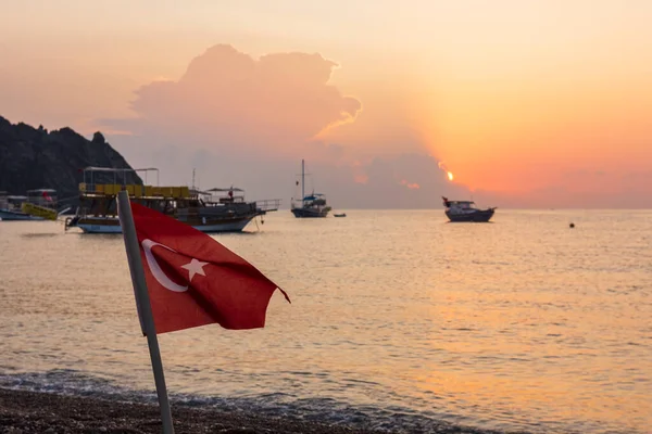 Cirali köyündeki sahilde sabah. Taurus dağının yakınındaki gemiler ve gemiler kıyıya demirlemiştir. Lycian Patikası 'nın manzaraları. Türk bayrağı