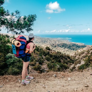 Sırt çantalı genç bayan gezgin güzel bir manzara, deniz ve tepeler, Afrodit Burnu, Kıbrıs yaz tatili için popüler bir yer.