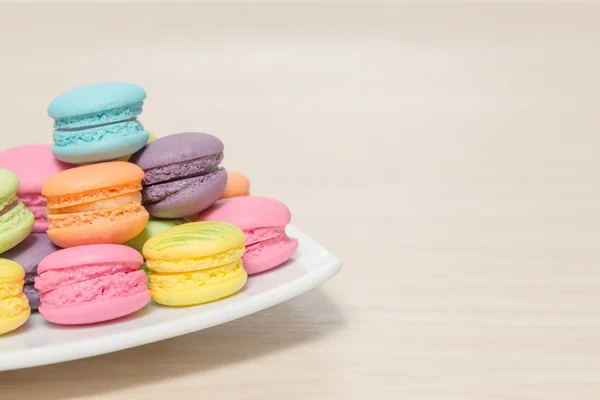 Stack of colorful macaroons cookies in dish on wood background w — Stock Photo, Image