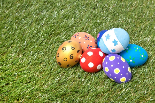 Montón de coloridos huevos de Pascua hechos a mano en la hierba — Foto de Stock