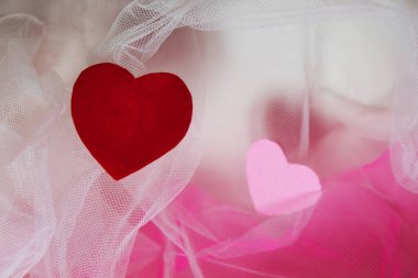 Sevgililer Günü için kalpleri ve çiçekleri olan pembe tekstil arka planında hatıra oyuncak ayılar.