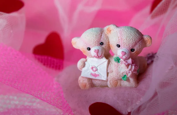 Sevgililer Günü için kalpleri olan pembe tekstil arka planında oyuncak ayılar.