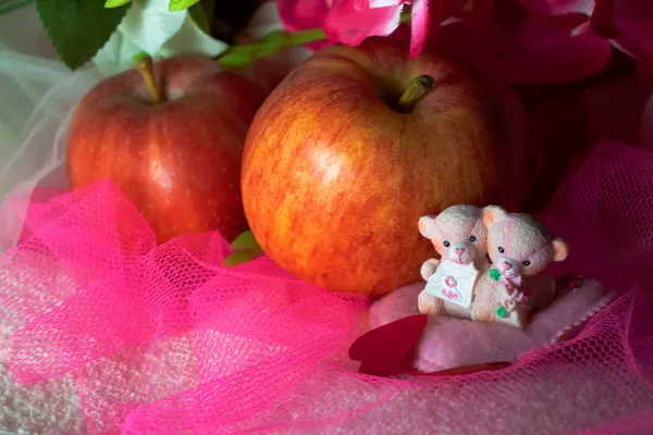 Sevgililer Günü için kalpleri ve çiçekleri olan pembe tekstil arka planında hatıra oyuncak ayılar.