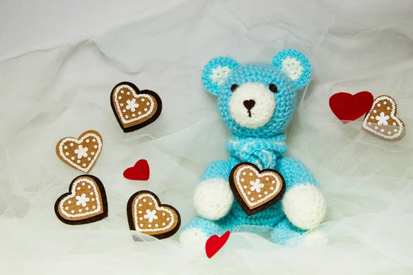 Beyaz arka planda kalpleri olan mavi örülü bir ayı.