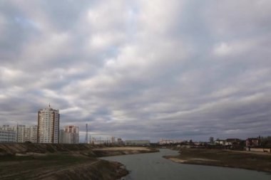 Yüksek binalar ile bir şehir üzerinde karanlık bulutlu gökyüzü.