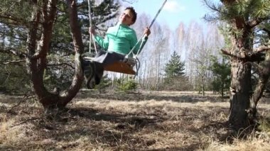 Gomel, Belarus - 3 Nisan 2016: Aile bir orman glade binmek bir salıncak üzerinde.