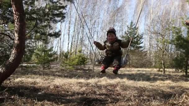 Homel, Wit-Rusland - 3 April 2016: Familie in een bos glade rit op een schommel. — Stockvideo