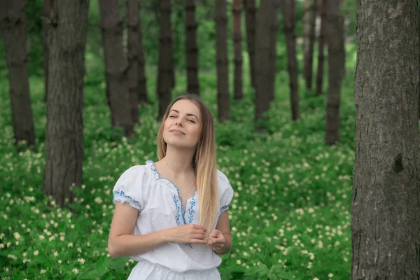 Belle jeune fille en gros plan dans une chemise blanche, sur un fond de forêt verte — Photo