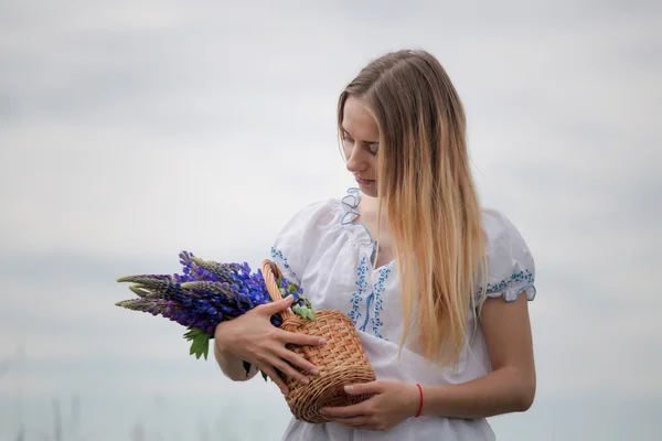 Portret van mooie jonge vrouw met bloemen op het gebied — Stockfoto