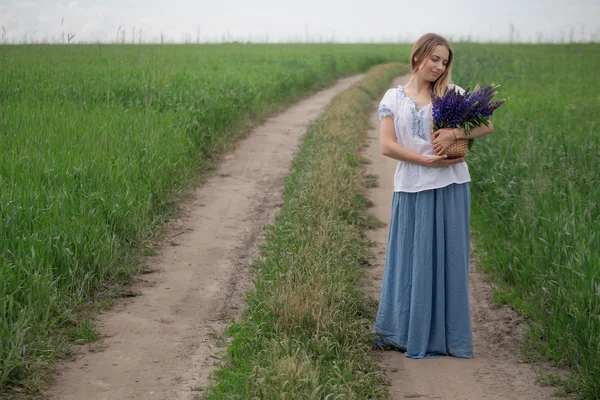 Porträt einer schönen jungen Frau mit Blumen auf dem Feld — Stockfoto