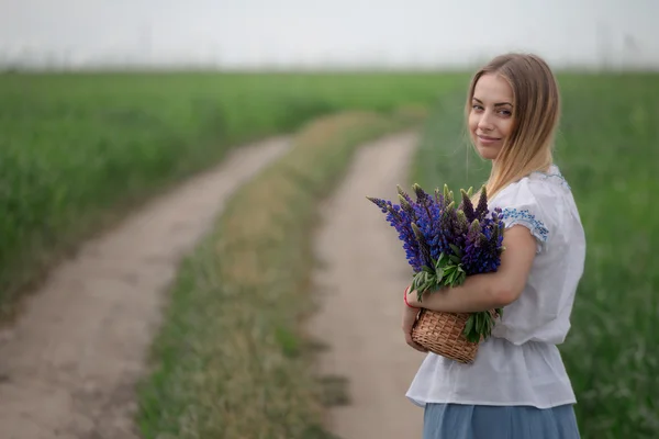 Retrato de bela jovem com flores no campo — Fotografia de Stock