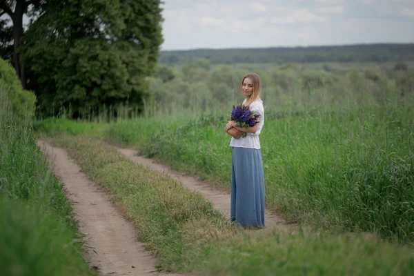Porträtt av vacker ung kvinna med blommor i fältet — Stockfoto