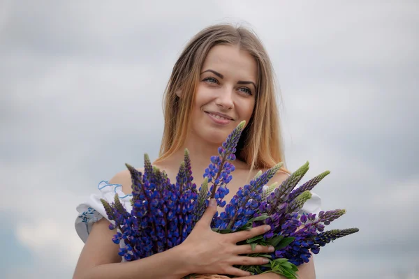 Portret van mooie jonge vrouw met bloemen op het gebied — Stockfoto