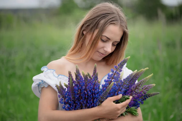 Retrato de bela jovem com flores no campo — Fotografia de Stock