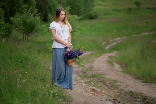 Porträt einer schönen jungen Frau mit Blumen auf dem Feld — Stockfoto