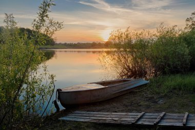 Güzel yaz gün batımında mavi gökyüzü, kırmızı ve turuncu bulutlar, yeşil ağaçlar ve su Nehri