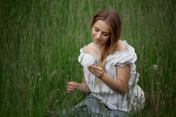 Chica rubia en pantalones cortos sentados en la hierba al aire libre — Foto de Stock