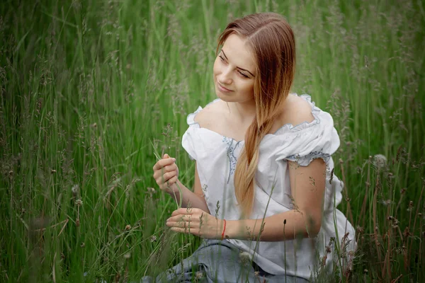 Chica rubia en pantalones cortos sentados en la hierba al aire libre — Foto de Stock