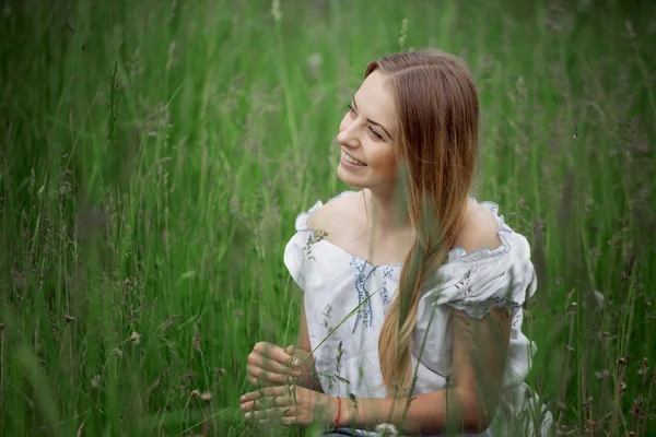 Chica rubia en pantalones cortos sentados en la hierba al aire libre — Foto de Stock