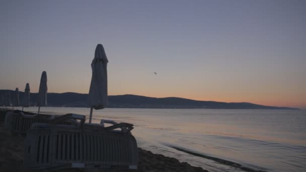 Sol nascendo ao longo do horizonte e ondas de surf de mar de manhã na praia arenosa — Vídeo de Stock