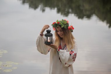 bir çelenk ile geleneksel beyaz elbiseli genç güzel kız