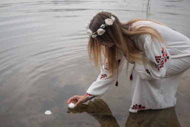 bir çelenk ile geleneksel beyaz elbiseli genç güzel kız