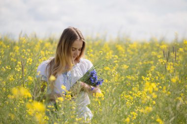 başında, bir çiçekli sarı alanda renkli çiçek çelenk ile kız