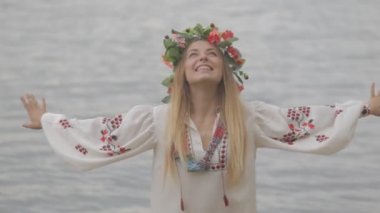 bir çelenk ile geleneksel beyaz elbiseli genç güzel kız