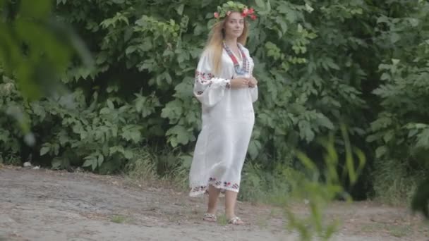 Bir çelenk ile geleneksel beyaz elbiseli genç güzel kız — Stok video