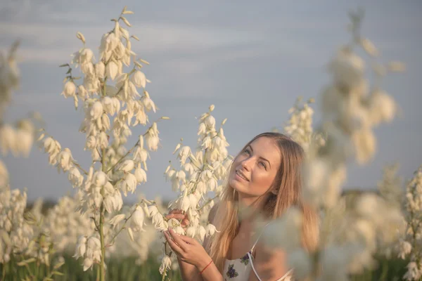 Princesa. Joven hermosa mujer bonita posando en vestido de lujo larga noche contra los arbustos con flores blancas — Foto de Stock