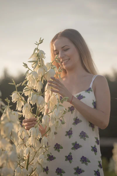 Princess. Young beautiful pretty woman posing in long evening luxury dress against bushes with white flowers