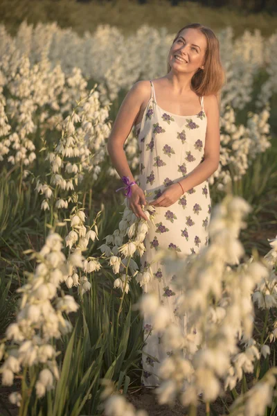 Princesa. Joven hermosa mujer bonita posando en vestido de lujo larga noche contra los arbustos con flores blancas —  Fotos de Stock