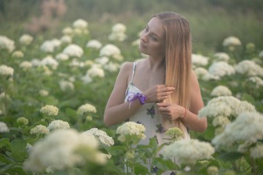 beyaz çiçekli yeşil bir alanda yürüyüş akşam güneşin sıcak ışınları genç güzel kadın.