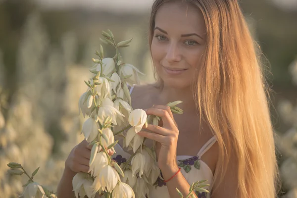 Princesa. Joven hermosa mujer bonita posando en vestido largo en contra en el campo con flores blancas —  Fotos de Stock