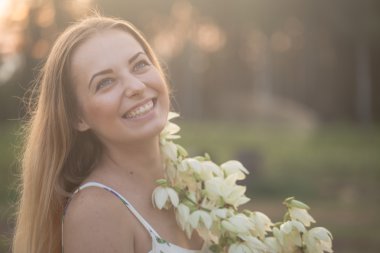 yakın çekim portre... Genç güzel güzel kadın beyaz çiçekli alanında karşı uzun elbise poz