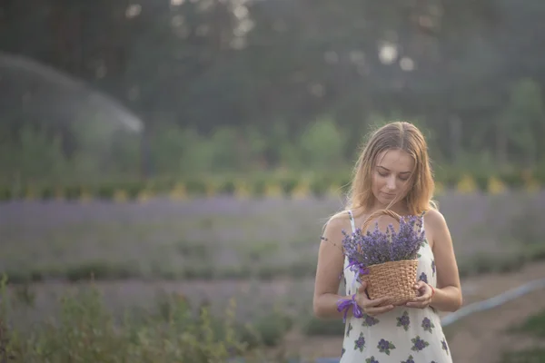 Souriante fille reniflant des fleurs dans un champ de lavande — Photo