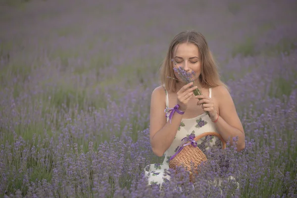 Chica sonriente oliendo flores en un campo de lavanda —  Fotos de Stock