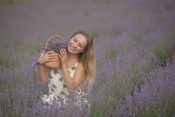 Souriante fille reniflant des fleurs dans un champ de lavande — Photo