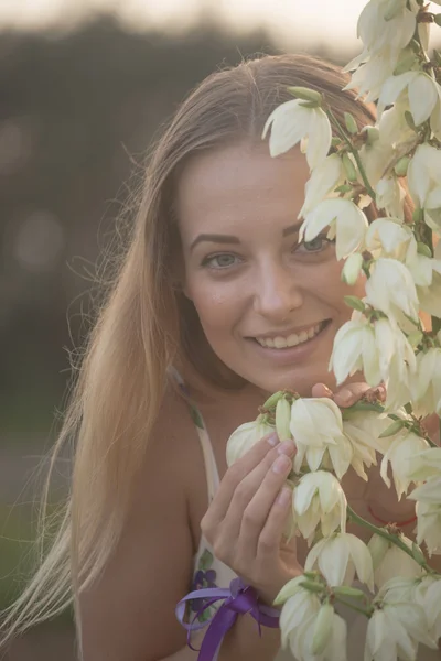 Portrait en gros plan.. Jeune belle jolie femme posant en robe longue contre dans le domaine avec des fleurs blanches — Photo