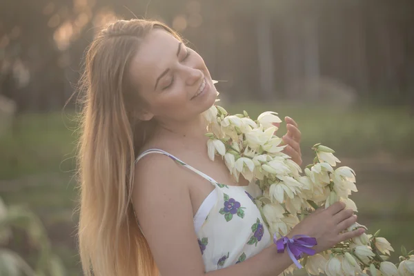 Portrait en gros plan.. Jeune belle jolie femme posant en robe longue contre dans le domaine avec des fleurs blanches — Photo