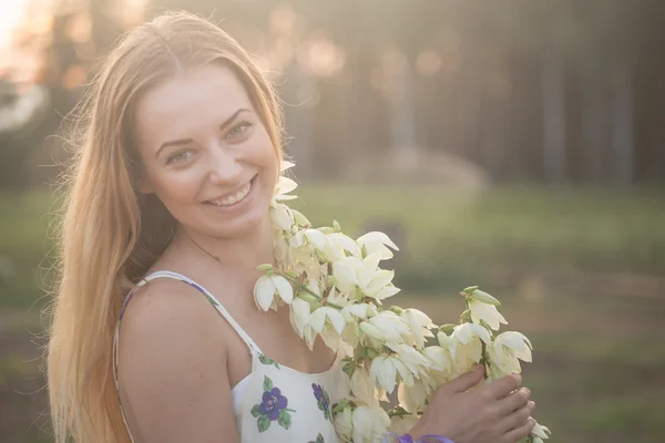 Portrait en gros plan.. Jeune belle jolie femme posant en robe longue contre dans le domaine avec des fleurs blanches — Photo