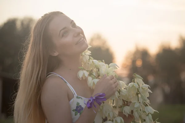 Portrait en gros plan.. Jeune belle jolie femme posant en robe longue contre dans le domaine avec des fleurs blanches — Photo