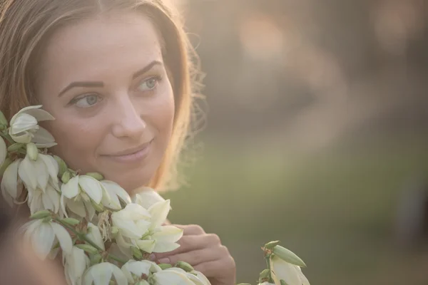 Portrait en gros plan.. Jeune belle jolie femme posant en robe longue contre dans le domaine avec des fleurs blanches — Photo