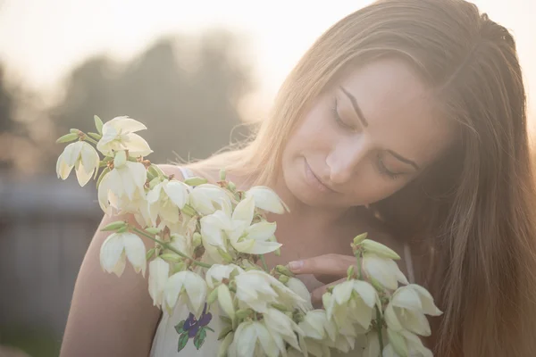 Close-up retrato.. Jovem bela mulher bonita posando em vestido longo contra no campo com flores brancas — Fotografia de Stock
