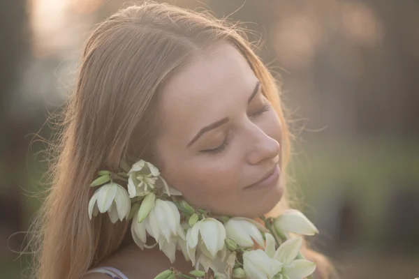 Közeli portré... Fiatal gyönyörű szép nő pózol hosszú ruha, ellen, fehér virágok területén — Stock Fotó
