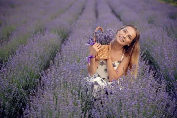 Mosolygó lány szippantás a virágok levendula mező — Stock Fotó
